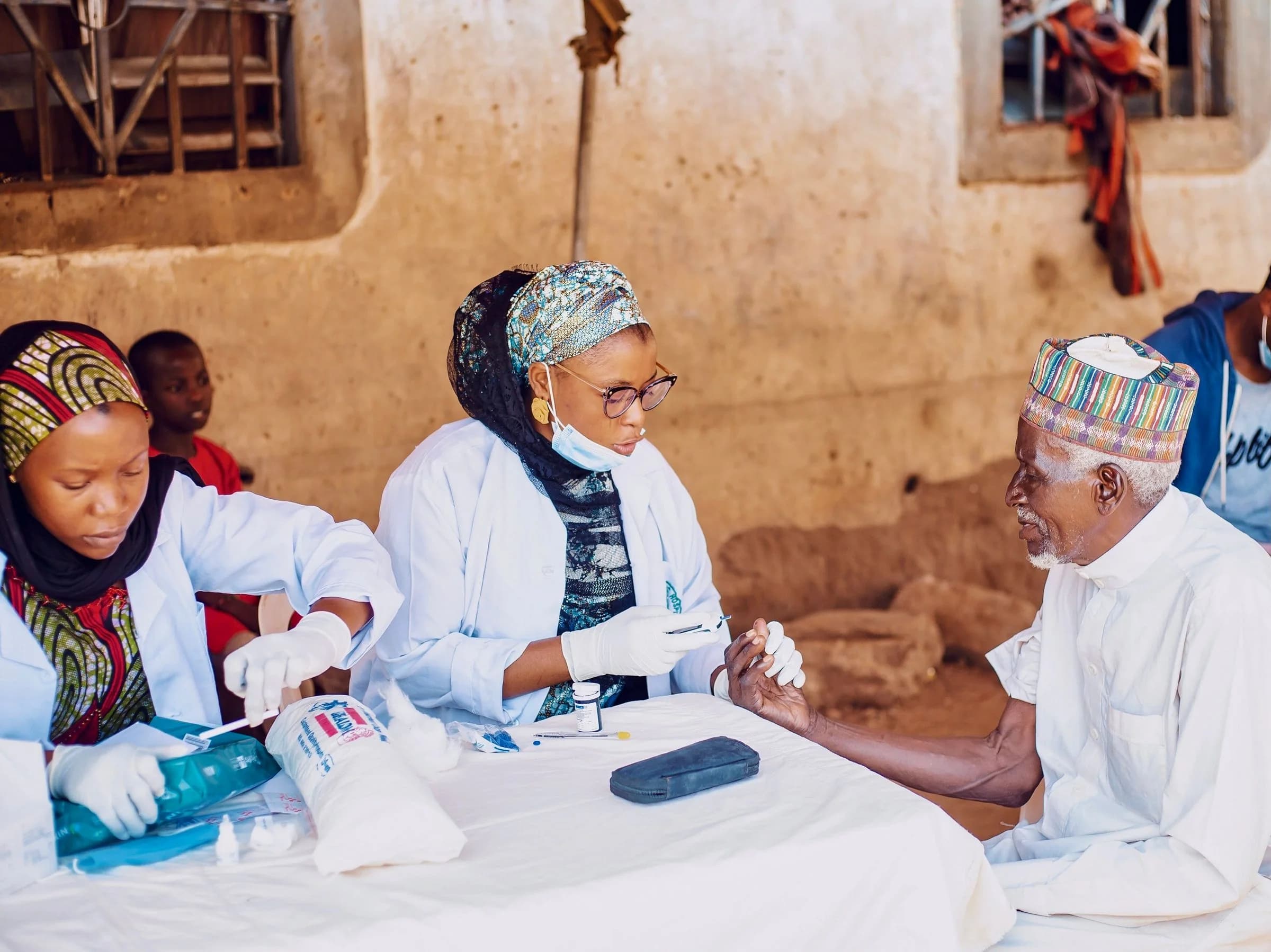 Illustrative stock photograph of healthcare workers assisting an older man during a community medical outreach in Kaduna, Nigeria; this is not a CVID-CAM activity