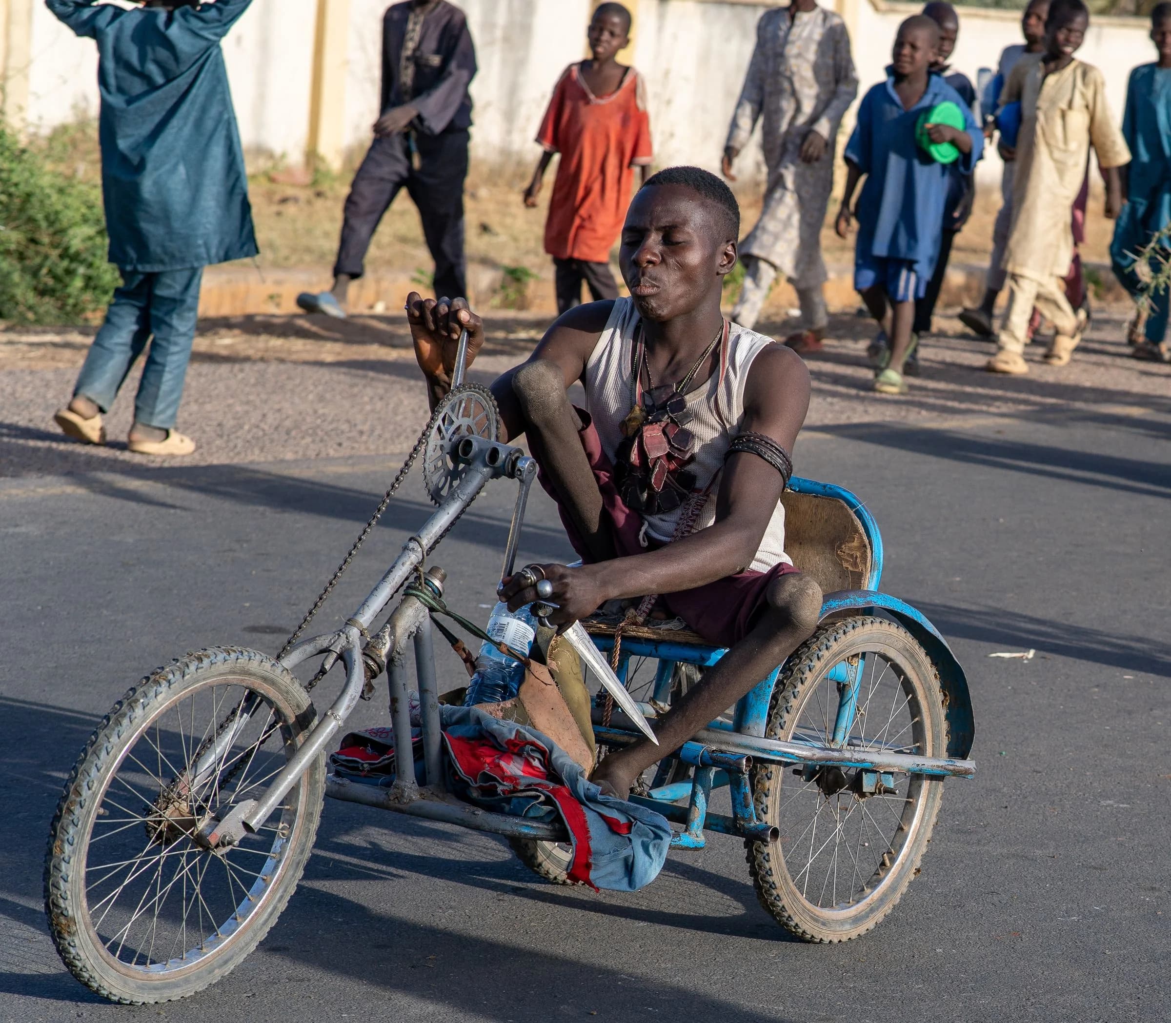Illustrative stock photograph of a man using a locally made wheelchair on a community street in Dutse, Nigeria; this is not a CVID-CAM activity